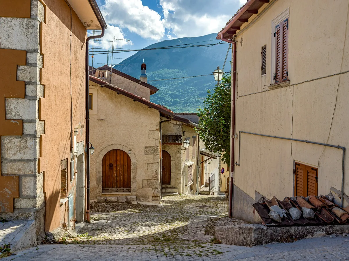 Strada in un borgo abruzzese con montagne sullo sfondo